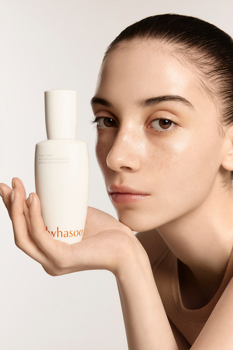 A model holding First Care Activating Serum VI in one hand